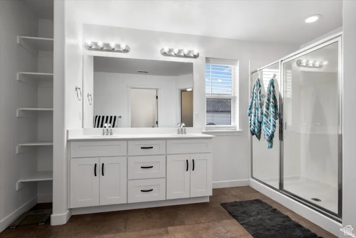 Bathroom featuring a double vanity with white cabinetry, dual sinks, and a large mirror