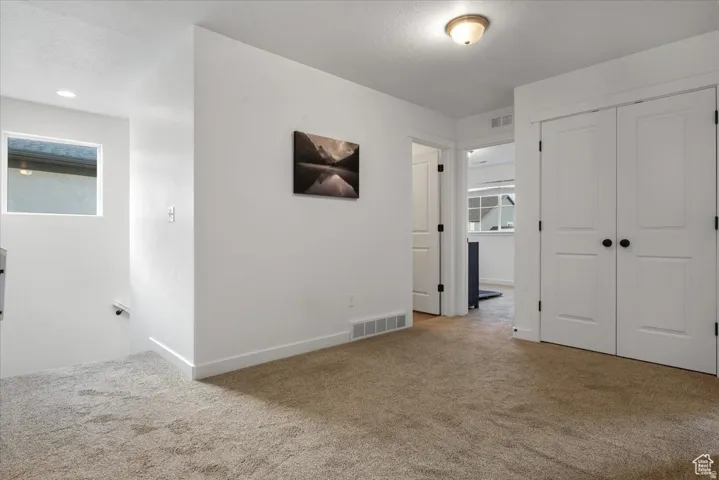 Carpeted landing area featuring a white railing, a rectangular window, recessed lighting, and a flush-mount ceiling light