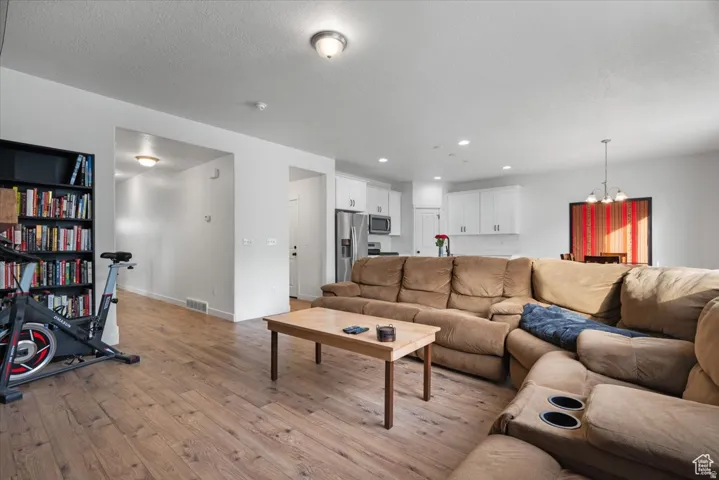 Expansive living area featuring wood-finish flooring, white walls, and recessed lighting