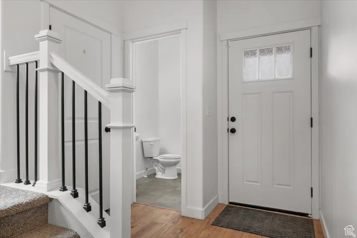 Entryway featuring wood-finish flooring, a white paneled door with frosted glass detailing, and black hardware