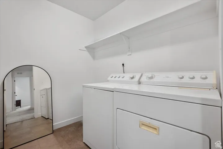 Dedicated laundry area featuring white appliances and integrated shelving