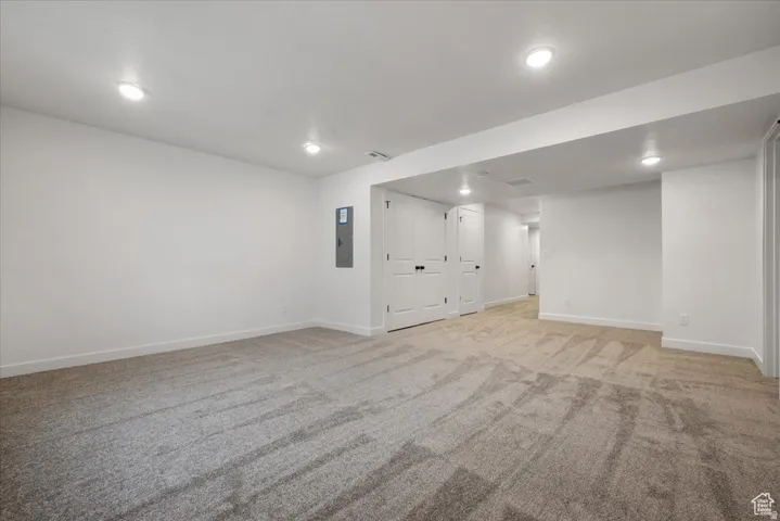 Spacious interior room with light-toned carpeting and recessed ceiling lighting