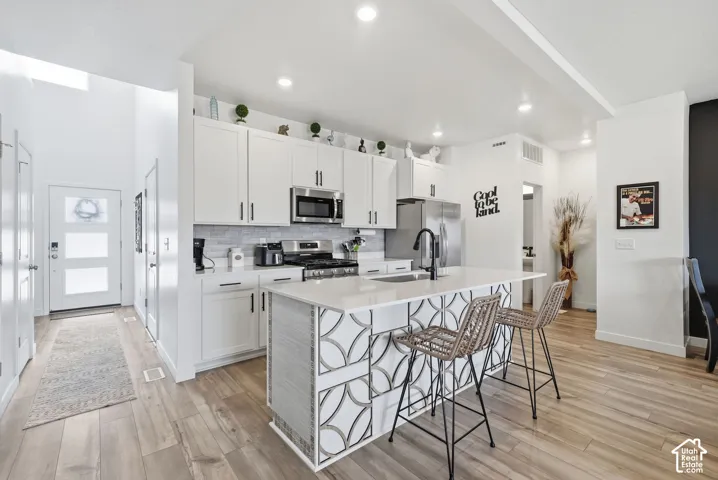 Modern kitchen featuring white cabinetry, stainless steel appliances, and a central island with decorative paneling