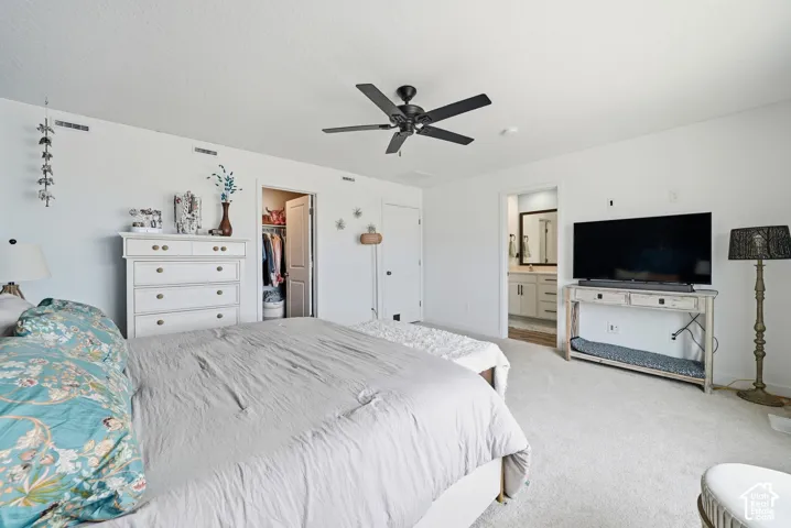 Spacious bedroom featuring light-colored carpeting, a black ceiling fan, and white walls