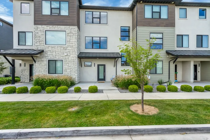 Modern townhome facade featuring a  stucco exterior with dark trim accents