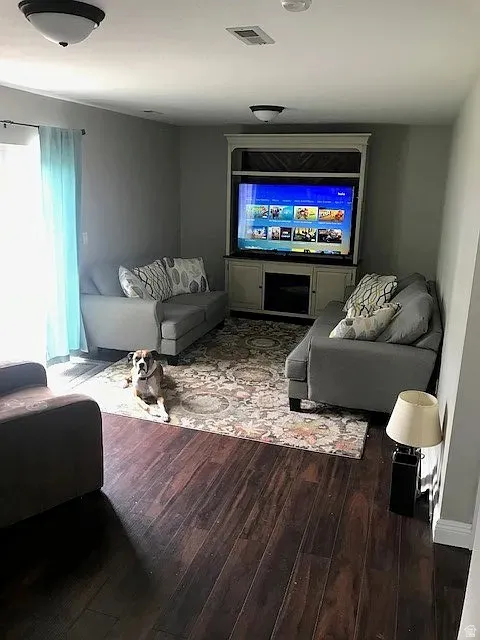 Living area featuring dark wood-finish flooring, a built-in media console, and neutral wall tones