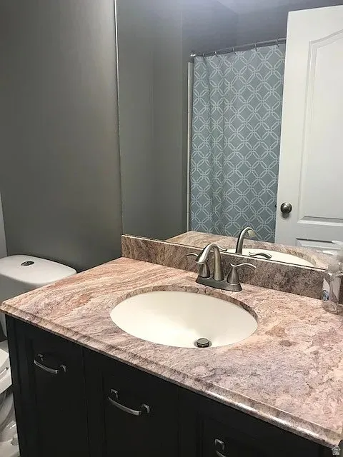 Master Bathroom vanity featuring a built-in oval sink, a patterned countertop, a wall-mounted mirror, and dark cabinetry with brushed nickel hardware