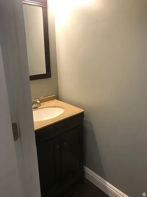 Main floor half bath, featuring a dark wood vanity with a light-toned countertop, an integrated oval sink, and a framed mirror