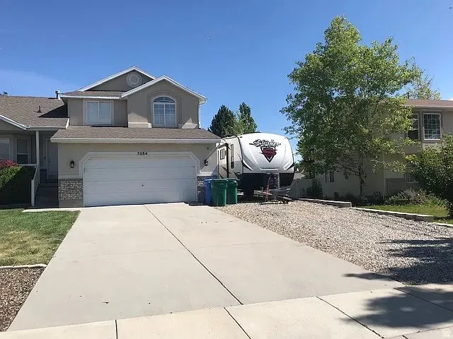 Two-story residence featuring a two-car garage, stone accents, arched window, and a concrete driveway