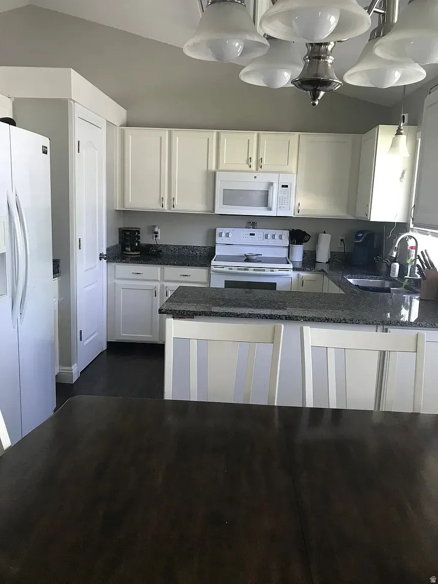 Kitchen featuring white cabinetry, dark speckled countertops, and an integrated white microwave