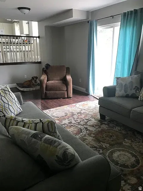 Open-concept living area featuring wood-finish flooring, a sliding glass door, and an interior half-wall with white balusters