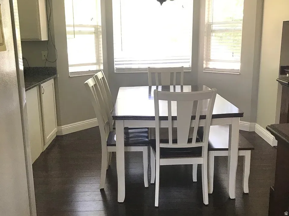 Bay window dining area featuring dark wood-finish flooring, white baseboards, and light gray wall paint