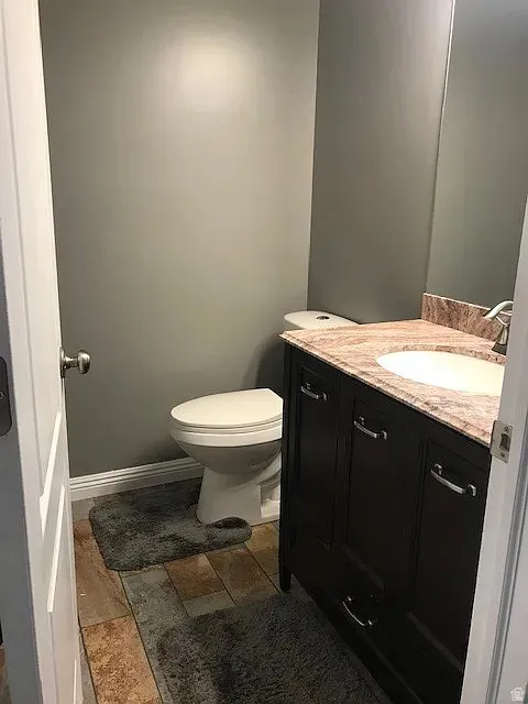 Master Bathroom featuring a dark wood vanity with a white basin sink, a stone-finish countertop, and a contemporary faucet
