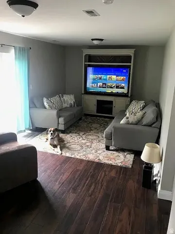 Living area featuring dark wood-finish flooring, a built-in media console, and neutral wall tones