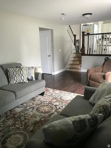 Open concept living area featuring dark wood-finish flooring, a neutral wall palette, and a staircase with dark wood railings
