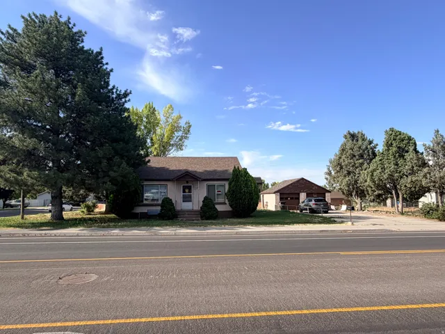 Single-story property with a detached garage and a front lawn featuring mature trees