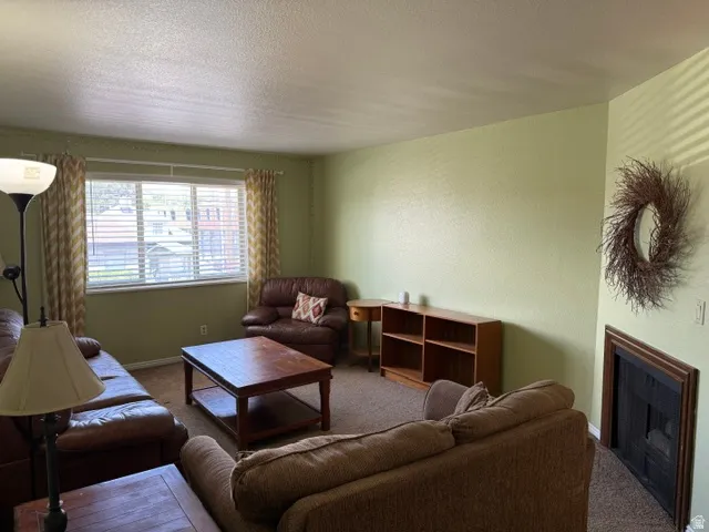 Living area featuring light green walls, a large window with blinds, and a built-in fireplace