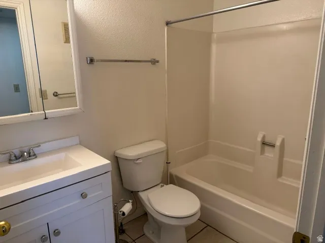 Bathroom featuring a white vanity with integrated sink, chrome faucet, wall-mounted mirror, toilet, and a white tub/shower combination