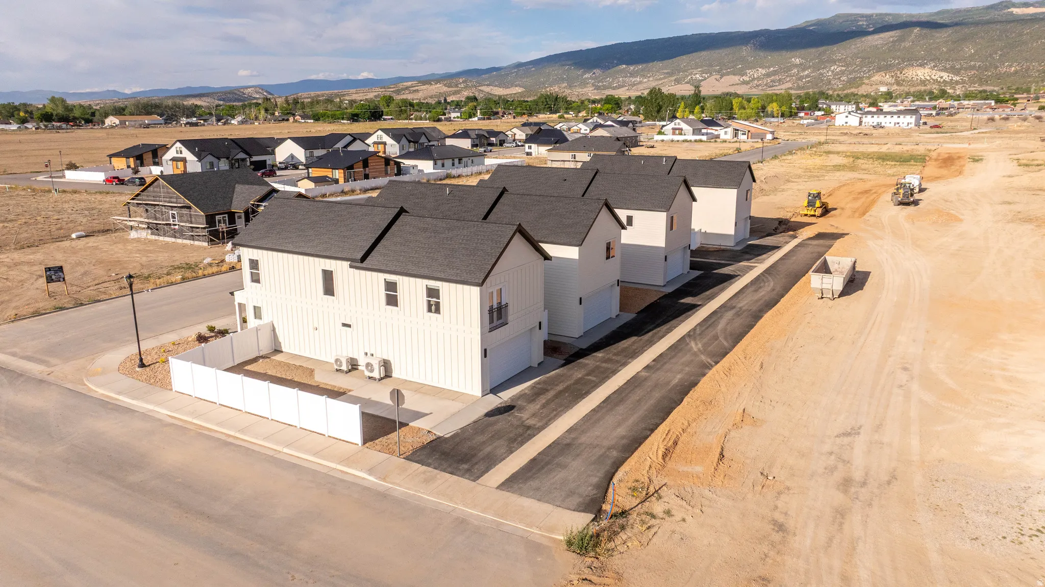 Newly constructed homes featuring white vertical siding, black asphalt shingle roofs, and attached garages