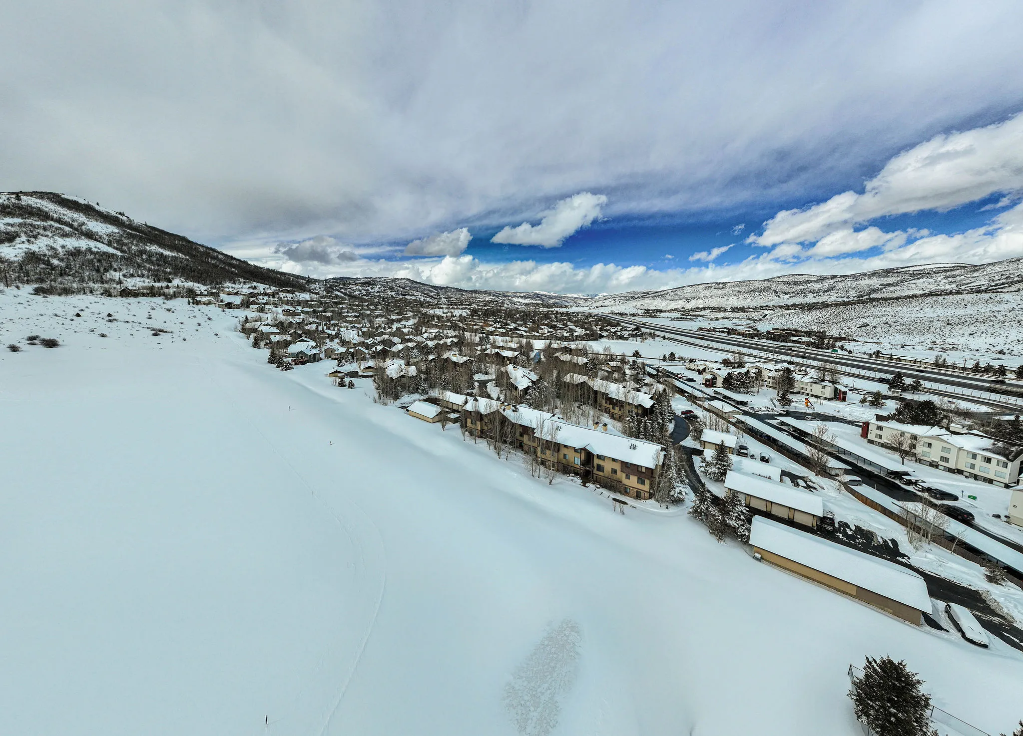Aerial perspective showcasing a community of homes nestled in a snow-covered mountain valley