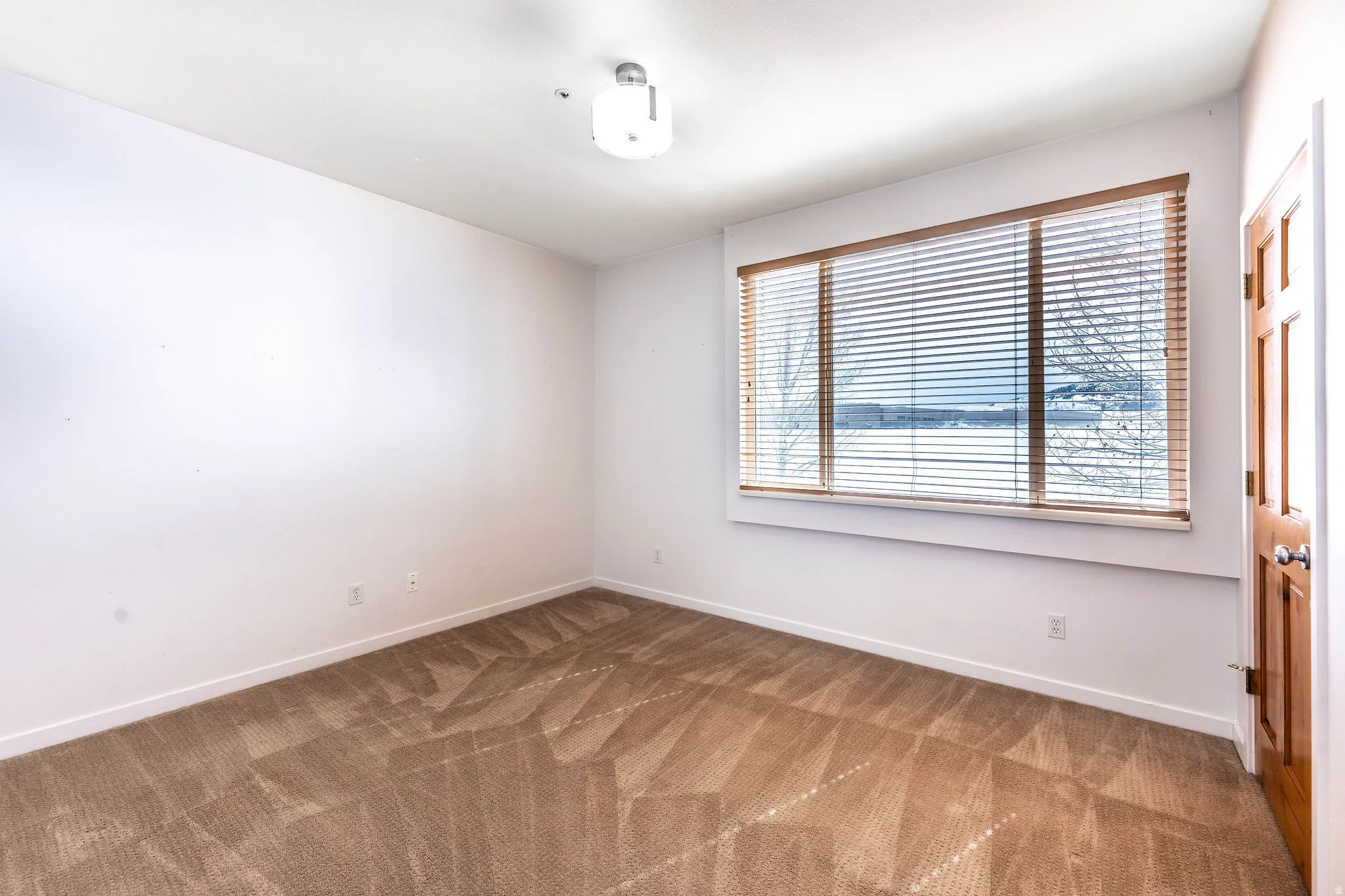 Neutral white walls with a large window featuring horizontal blinds