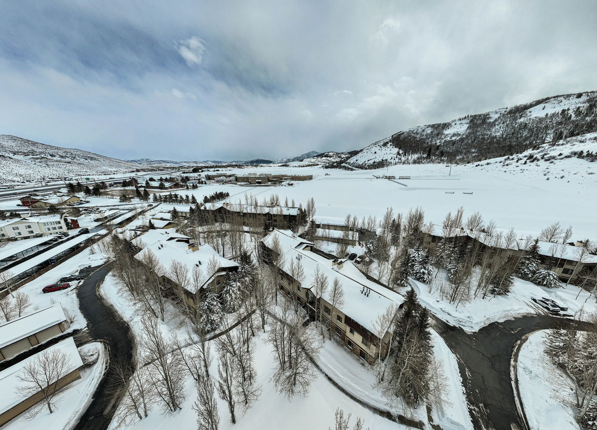 Snow-covered mountain community with multiple residential buildings featuring pitched roofs and varying architectural styles