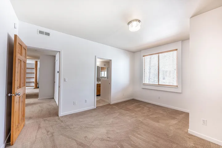 Carpeted room with a ceiling-mounted light fixture and a window featuring horizontal blinds
