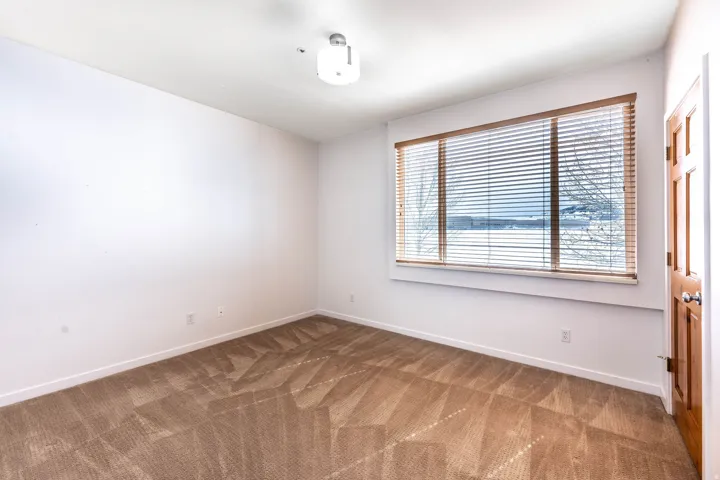 Neutral white walls with a large window featuring horizontal blinds