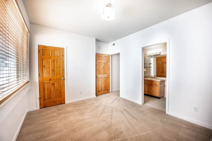 Spacious room featuring neutral carpet flooring, white walls, and natural wood doors