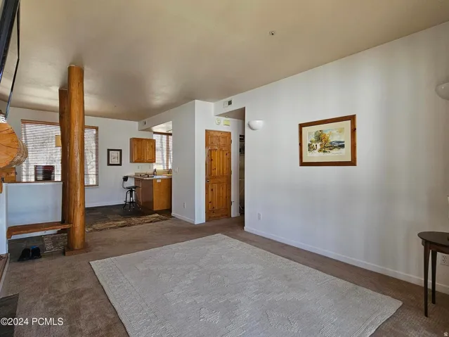 Spacious living area featuring neutral carpeting and white wall finishes