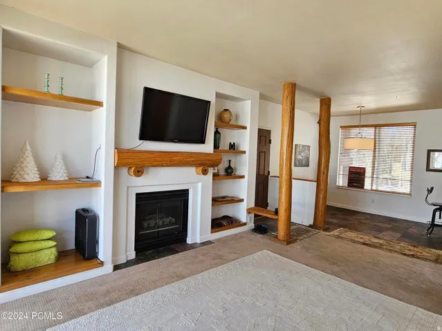 Living area featuring a fireplace with a wood mantle and built-in shelving