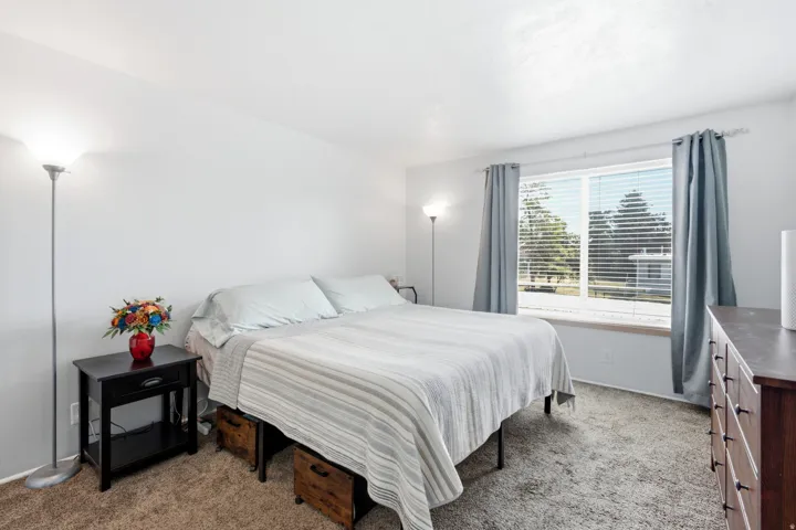Carpeted room featuring a large window with blinds and drapes, white walls, and a flat ceiling