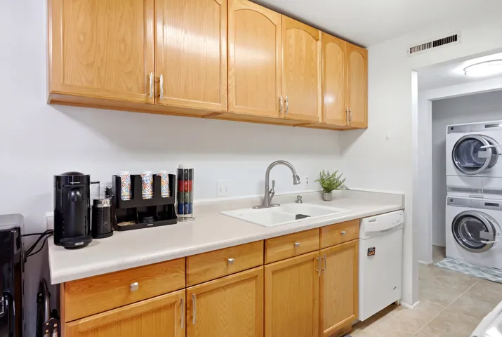 Wood-finish cabinetry paired with a light-toned countertop and a dual-basin sink with a gooseneck faucet