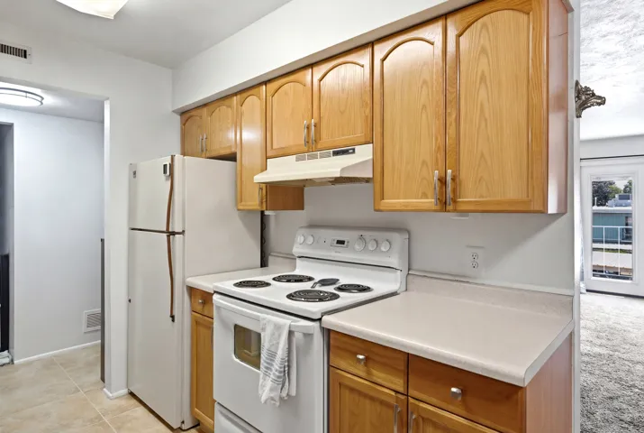 Kitchen featuring light wood cabinetry with arched top panels and silver-tone hardware