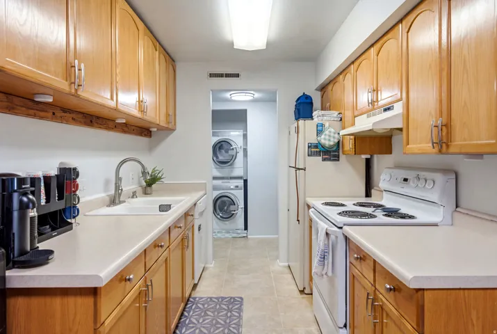 Kitchen featuring wood-finish cabinetry, solid surface countertops, and a white sink with a gooseneck faucet