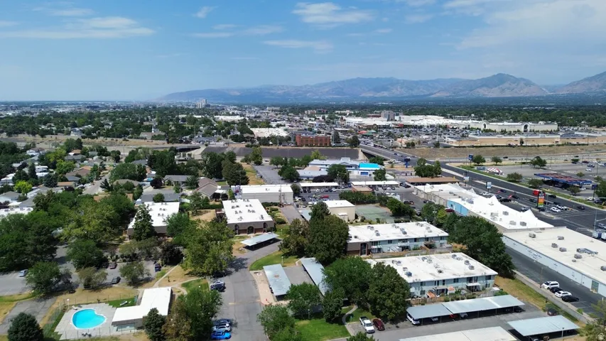 Aerial perspective showcasing a mixed-use neighborhood with residential buildings, commercial structures, and a prominent swimming pool