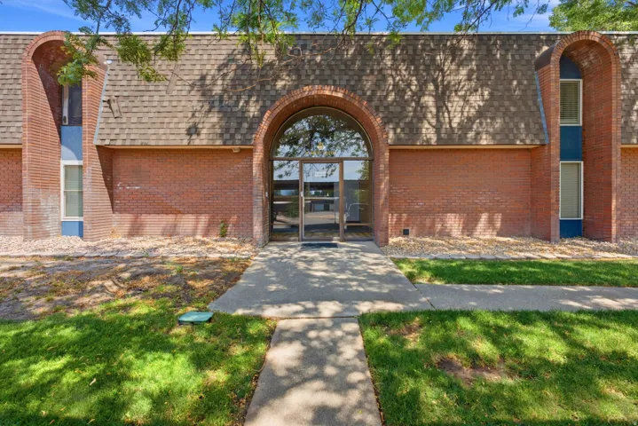Brick exterior featuring an arched glass entry, a pitched shingle roof, and a concrete walkway