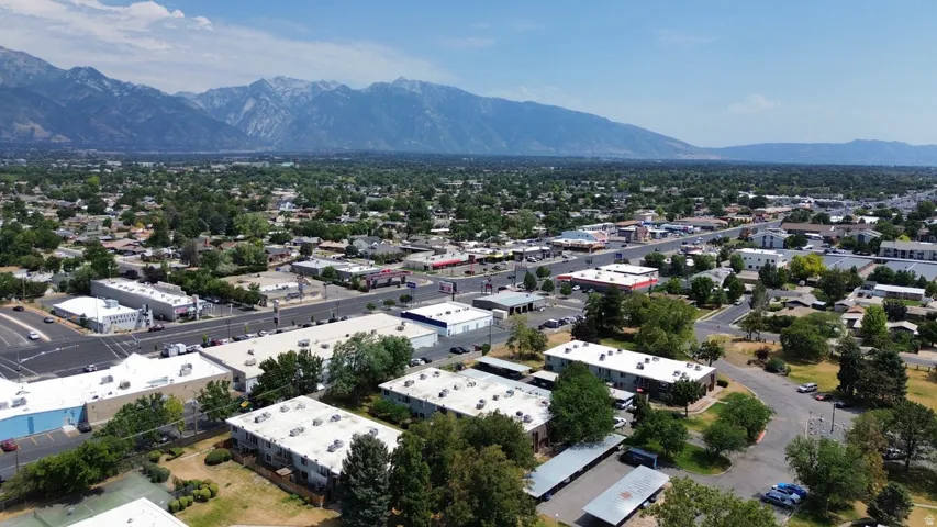 Aerial perspective showcasing a developed area with extensive tree coverage and a prominent mountain range in the background