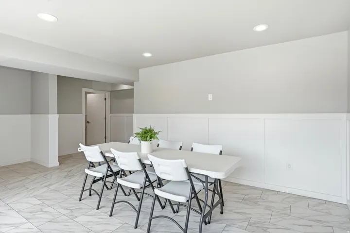 Spacious room featuring light-toned walls, white wainscoting, recessed lighting, and patterned tile flooring