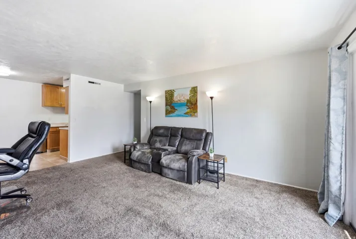 Spacious living area featuring neutral carpeting and light-colored walls