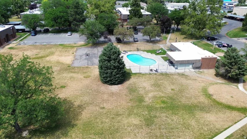 Outdoor swimming pool with surrounding fence, adjacent building with flat roof, and expansive grassy areas