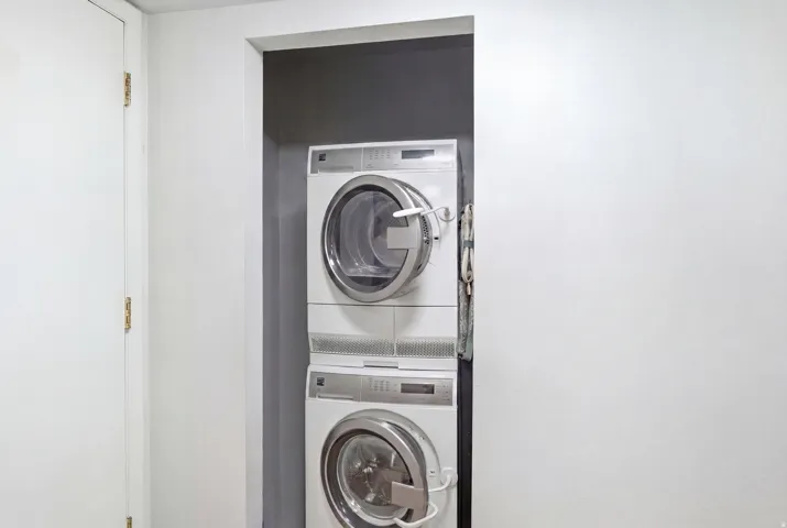 Laundry area featuring a stacked washer and dryer unit within an alcove