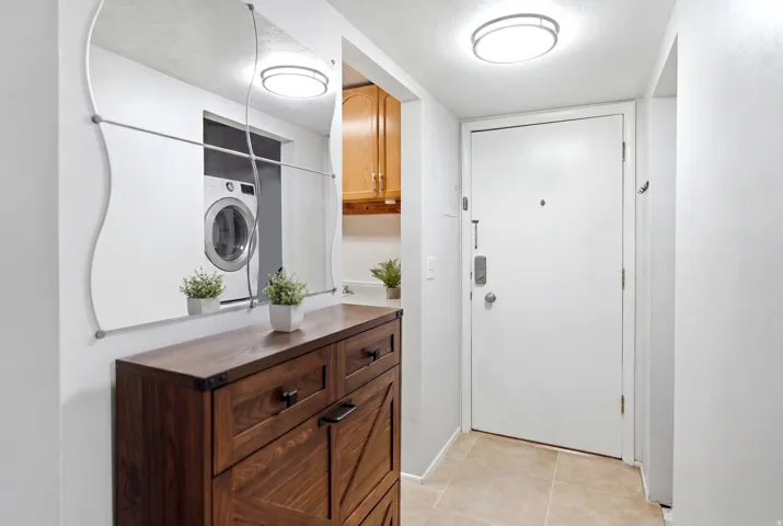 Foyer with a wood-finish storage console, decorative wall mirror, and light-toned floor tiling