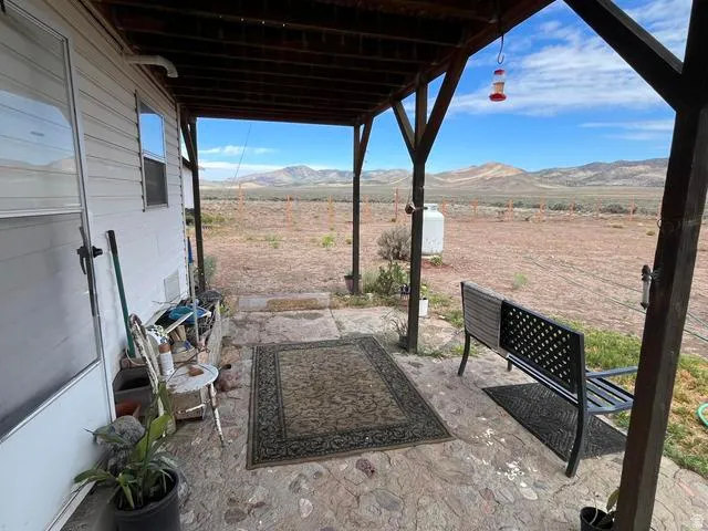 Expansive covered porch featuring a stone patio, exposed wood beam ceiling, and a large propane tank