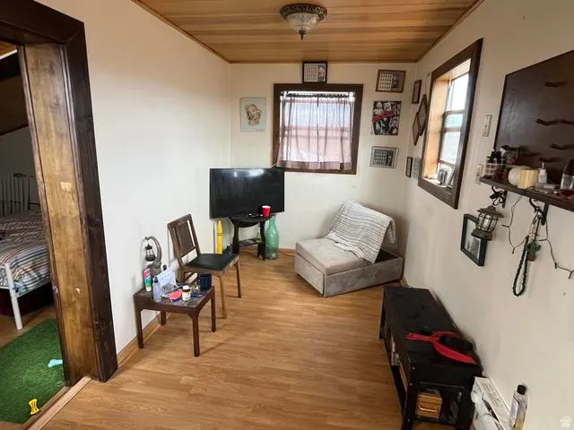 Room featuring wood-finish flooring, a wood-paneled ceiling, and white painted walls