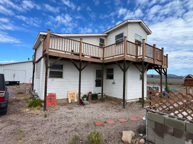 Two-story residence featuring white siding and a large second-level wood-finish deck with railings