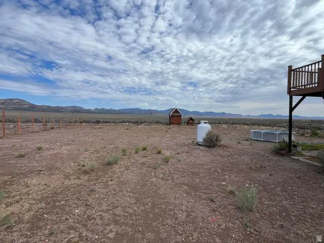 Expansive outdoor space featuring a brown soil ground, distant mountains, and a large propane tank