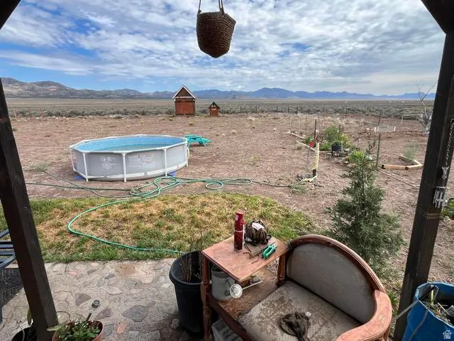 Expansive outdoor area featuring a stone patio, an above-ground pool, and a structured gardening space