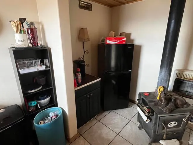 Tile flooring anchors this space featuring a black wood-burning stove with a prominent flue