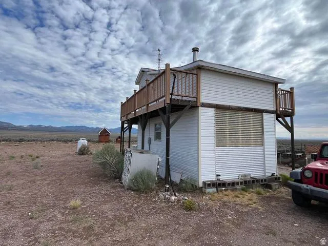 Two-story structure featuring white horizontal siding and a wood-decked upper level